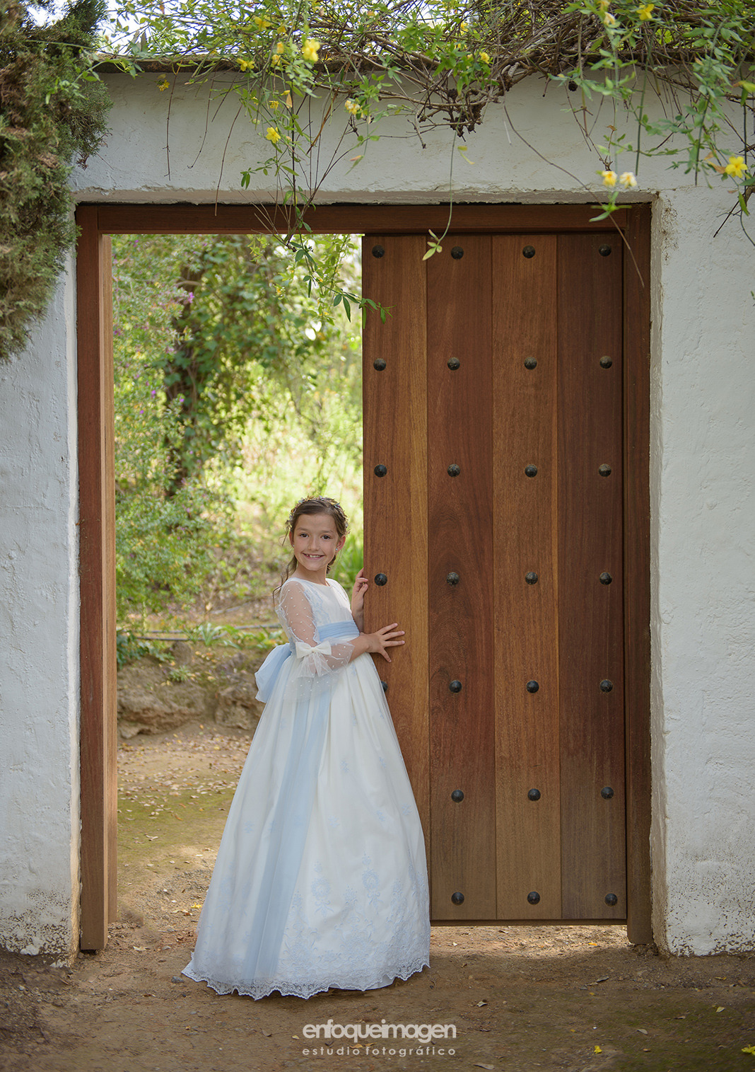 Fotografía de niña de Primera Comunión junto a una puerta en exterior