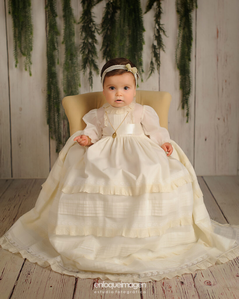 fotografia de bebe vestida con baton de bautizo y medalla en estudio de fotos