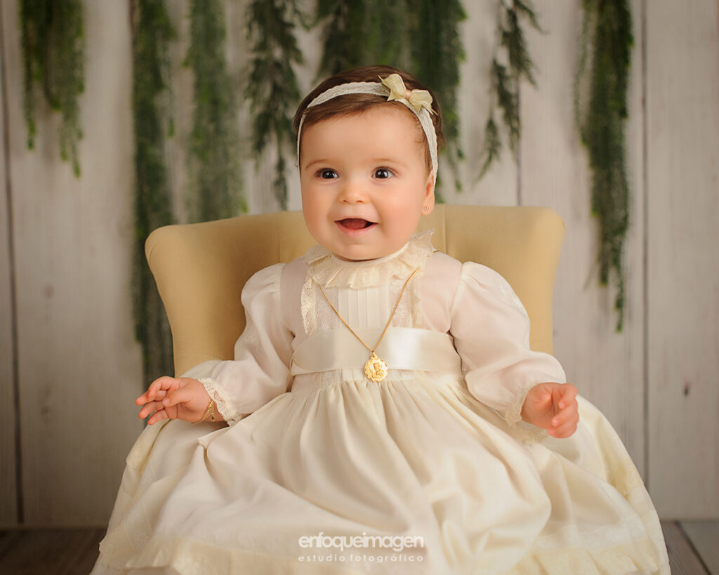 fotografia de bebe vestida con baton de bautizo y medalla en estudio de fotos