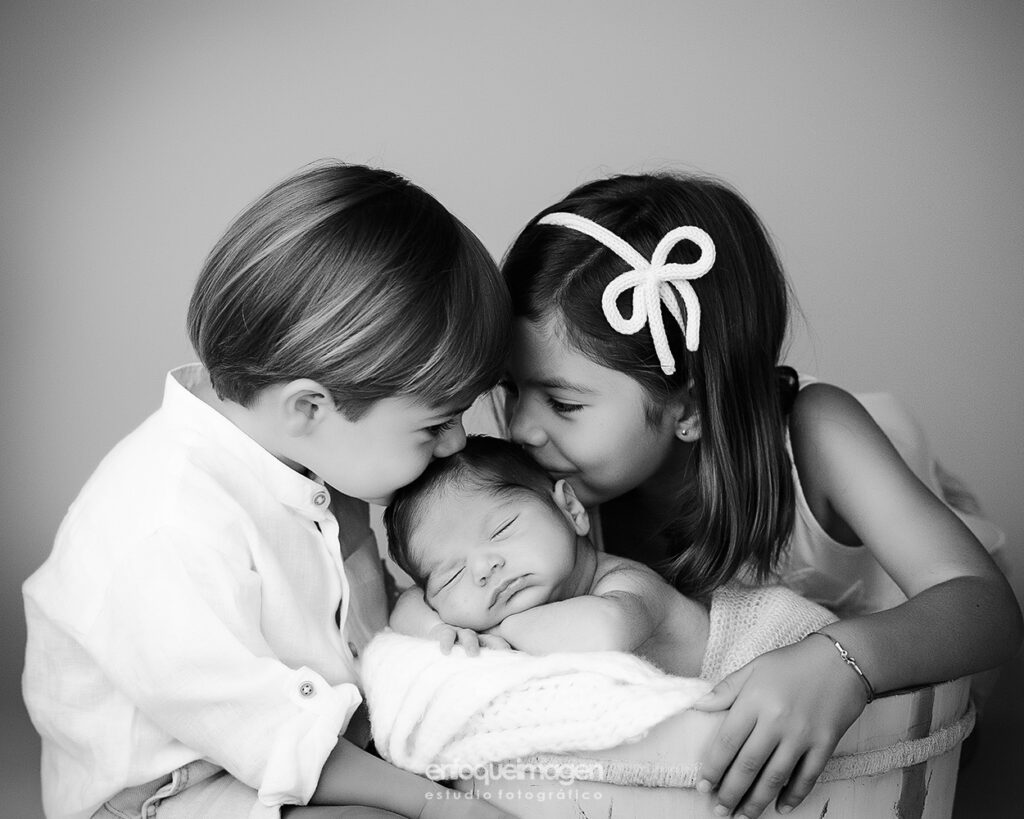 niño y niña con hermano recien nacido, fotografía en blanco y negro en estudio fotográfico, enfoqueimagen