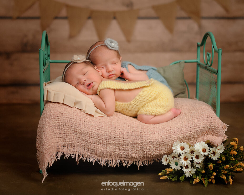 dos bebés mellizos recien nacidos durmiendo en una camita verde